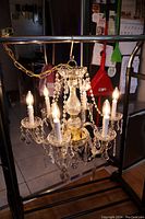 Chandelier lit with six bulbs showing crystal strands and glass arms.