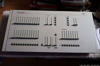 Full view of the Acclaim white metal lighting mixer control board with multiple slider faders arranged in groups, labeled Acclaim 100 series.