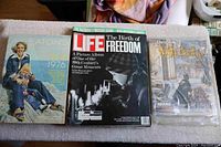 Three items displayed together: Eaton's 1976 catalog, Life magazine 'The Birth of Freedom', and Sears Wish Book 1995 catalog sealed in plastic.