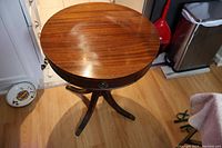Full view of the round wooden Duncan Phyfe drum table showing top surface, pedestal base, and legs.