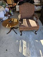 Armchair, coffee table, and lamp shown together on a concrete floor with natural light and visible shadows.