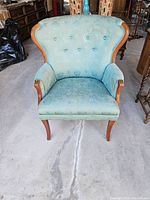 Front view showing entire wing back chair with blue floral upholstery and wooden legs.