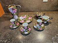 Full coffee service set displayed on countertop showing all pieces with floral rose design and gold trim