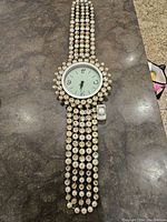 Photo showing both large decorative wall clock and small wristwatch on a dark surface.