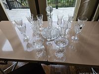 Full set displayed on table includes one crystal decanter with stopper and sixteen matching crystal glasses.
