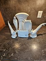 Overview of all six white porcelain decorative pieces on dark countertop.