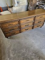 Photo of dresser top and nine drawers showing wood finish and metal pulls