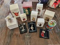 Full view of all 12 Hallmark Keepsake ornaments and decorations with their original packaging visible. Items include figurines, silver plated monogram ornaments, music note ornaments, and a snow globe.