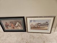 Two framed horse prints leaning against a beige wall; left shows three horse heads, right shows a horse race scene at a track with a lighthouse.