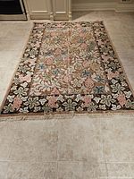 Full overhead view of rug laid on tiled floor showing overall pattern, border and fringe.