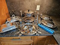 Overview of all pieces on countertop including covered dishes, chafing dish, trays, utensils and accessories