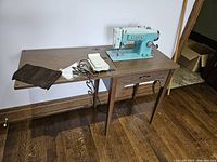 Vintage White 1964 sewing machine mounted on a wooden sewing machine table with folded and unfolded side extension shown.