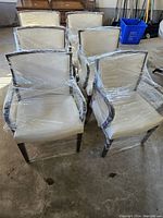 Six chairs wrapped in plastic film clustered in storage area