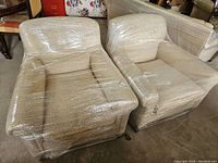 Two side chairs wrapped in plastic, front view