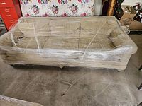 Front view of three-seat sofa wrapped in plastic film