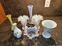Seven vases of mixed glass and porcelain on a countertop, showing overall lot