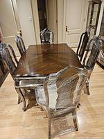 Full view of table and six chairs wrapped in plastic on hardwood floor