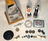 Grouped photo showing all items including the grater, figurines, buttons, tie clips, brooch, and enamel lid.