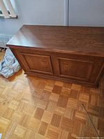 Photo showing the full front and top of the solid wood blanket chest. The chest has paneled doors and a medium brown wood finish.