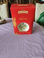 Front view of original red Bunnykins box for the baby set showing logo, product name, and an image of the plate.