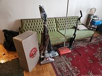 Photo shows retro Kirby vacuum cleaner, original Kirby box, second vacuum cleaner, and red manual sweeper.