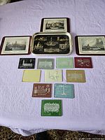 Full set of 14 items laid out on a bed including 3 trivets, 1 tray, and 10 glass coasters in various colors and designs.