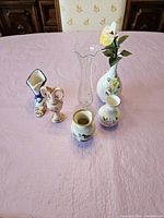 Photo showing full collection of 6 miniature vases arranged on a table with pink tablecloth.