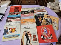Top view showing the full layout of the 20 vinyl albums on a purple cloth surface, titles visible to varying degrees.