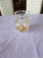 Clear and amber crystal vase on white tablecloth, showing shape and etched floral design.