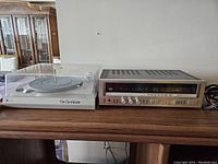 Receiver and turntable side by side on wooden surface