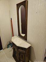 View of the entrance console table beneath the rectangular wooden-framed mirror mounted on the wall.