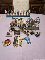 Photo showing entire Jewish collection of 13 pieces on a table, including two menorahs, figurines, candlesticks, and various Jewish symbols.