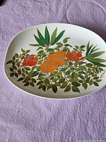 Oval Wolfe Bauer ceramic serving tray with detailed floral and leaf design on a white background, featuring orange and red flowers and green leaves.