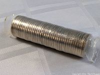 Roll of uncirculated Canadian 2000 nickels wrapped in original plastic wrap placed on a white cloth.