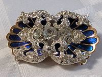 Close-up showing front detail of large vintage rhinestone and blue enamel pin brooch.