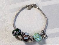 Full view of the sterling silver charm bracelet laid flat showing the clasp and bead charms attached.