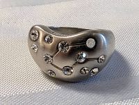 Close-up photo of sterling silver ring showing Libra constellation formed with multiple clear crystals and engraved lines.