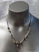 Front view of sterling silver necklace displayed on a black mannequin showing the chain and gemstone settings.