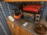 Photo of Black and Decker coffee maker, MasterChef toaster oven, George Foreman sandwich press, coffee filter holder, nutcracker on counter