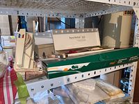 Shelf view showing the BBQ tools box, the white mixer appliance, and the white boxed cutlery set on the shelf.