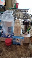 Full lot with vacuum bottles, Brita pitcher, glasses, and storage containers displayed on boxes
