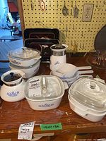 Full view of Corningware set on table showing various casserole dishes with lids, a teapot, and saucepans with the blue cornflower pattern