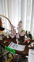 View of multiple vintage ceramic poodle and dog figurines arranged on a wooden surface, showing size and grouping.