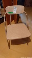 Front view of one beige cushioned foldable metal chair.
