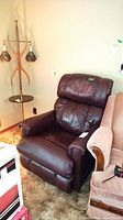 Photo showing overall view of the dark brown leather La-Z-Boy recliner chair positioned next to a wooden coat rack and a tan upholstered sofa.