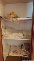 Shelves with folded lace table cloths and assorted fabric linens