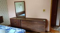 Full view of the vintage wooden dresser with attached mirror, showing its size and structure against a wall.