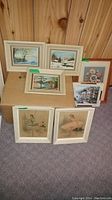 Seven framed artworks arranged on carpet and wooden box, showing general lot contents