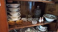 Side view of glassware and bowls inside a wooden cabinet shelf