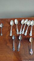Nine sterling silver spoons arranged with visible ornate handles and polished bowls.